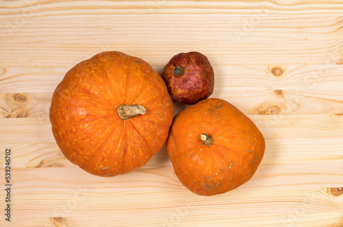 Yellow orange pumpkins and pomegranate on a light wooden table, Halloween concept and autumn pumpkin harvest, farm product
