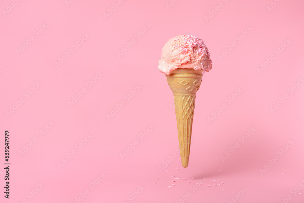 summer funny creative concept of flying wafer cone scoops of ice cream decorated with strewed sprinkles on pink background