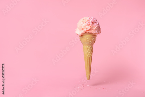 summer funny creative concept of flying wafer cone scoops of ice cream decorated with strewed sprinkles on pink background
