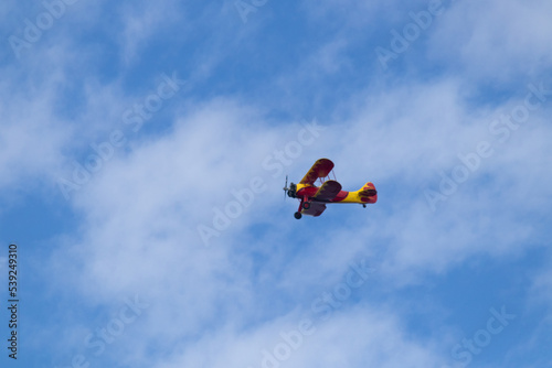 Little red biplane flying across semi cloudy sky. This plane almost reminded me of the red baron. It has such an old look to it. I took this picture while standing on the beach in Cape May New Jersey.