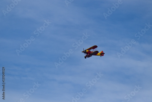 Little red biplane flying across semi cloudy sky. This plane almost reminded me of the red baron. It has such an old look to it. I took this picture while standing on the beach in Cape May New Jersey.