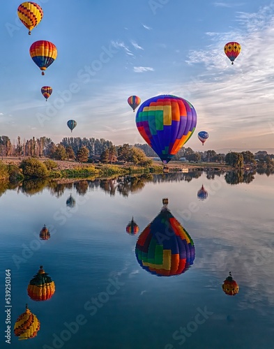 Vertical shot of air balloons in Prosser reflected in a river during the Washington balloon festival photo