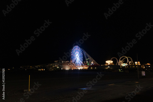 Love this image of the Wildwood pier lit up at night. The beautiful large ferris wheel, the white rollercoaster called the sea serpent and other rides seen below. This picture was taken in New Jersey.