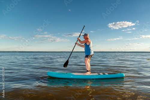 A man on a sup board against a clear blue sky. © finist_4