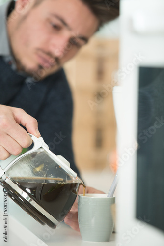 man in the kitchen pouring a mug of filtered coffee