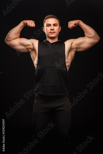 Strong athlete shows the muscles of the body on a black background