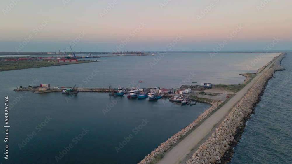 Aerial view of a harbor with fishing boats docked. Footage was taken from a drone at a higher altitude in summer season at sunset in Navodari harbor, Romania. Aerial view of a harbor with fishing boats docked. Footage was taken from a drone at a higher altitude in summer season at sunset in Navodari harbor, Romania.