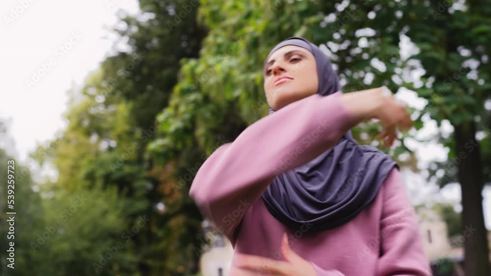 Closeup of athletic middle-eastern woman in hijab stretching in fresh air Closeup of athletic middle-eastern woman in hijab stretching in fresh air