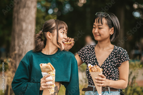 Cute young girls enjoying street food and looking entertained