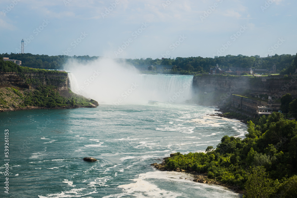 Niagara Horseshoe falls on sunset - blue water, haze and cloudy sky. Dramatic tones