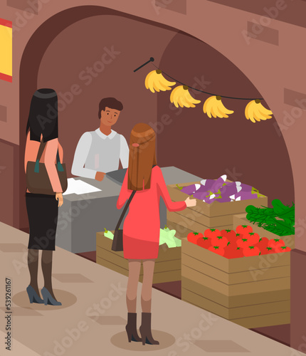 Tourists at eastern street bazaar, indian seller at counter sell vegetables and fruits. Asian street market with authentic goods. Local trade. Indian merchant, marketplace. Male seller sells products