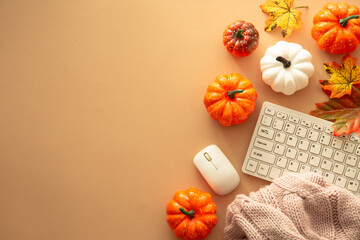 Autumn office workspace. Keyboard, laptop, notebok with autumn clothes and fall decorations - pumpkin, leaves and other. Fall flat lay.