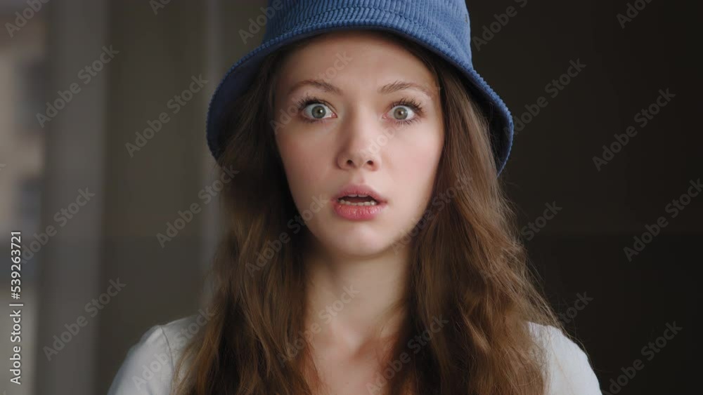 Close-up young frightened surprised woman standing indoors with wide open eyes and mouth in fright scared girl shocked by bad unbelievable news excited caucasian female student fears does not believe Close-up young frightened surprised woman standing indoors with wide open eyes and mouth in fright scared girl shocked by bad unbelievable news excited caucasian female student fears does not believe