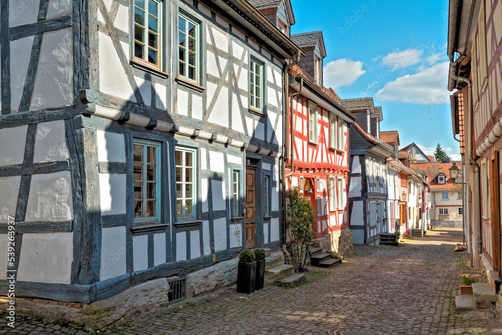 Gepflasterte Straße mit sanierten Fachwerkhäusern am Rand im historischen Stadtkern von Idstein im Taunus, Hessen, Deutschland