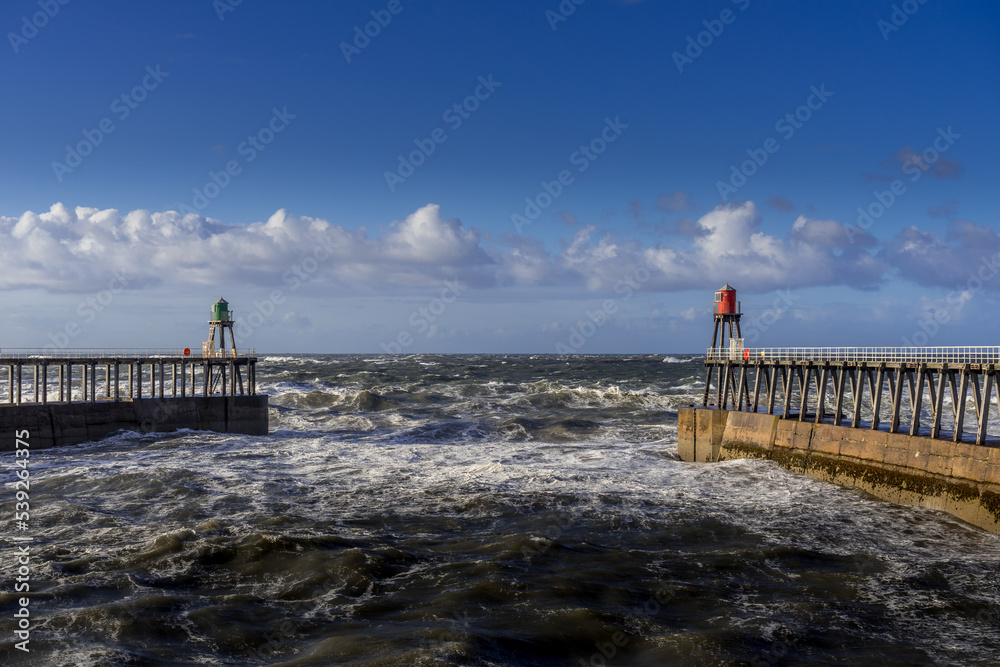 Fototapeta premium Looking out to sea from Whitby, North Yorkshire. The west and east piers frame the photo.
