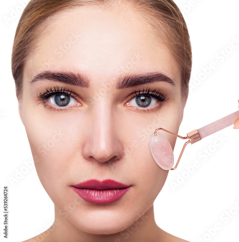 Young woman using pink quartz gua sha roller for face.