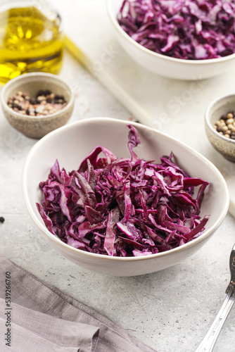 Two salad bowls with german red cabbage chopped in fine stripes on marble board on grey background