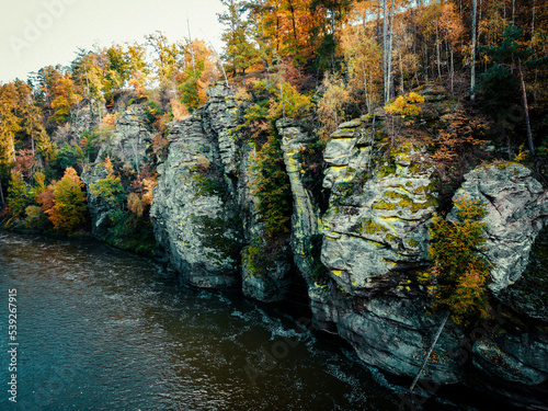 Rock and trees above river in autumn