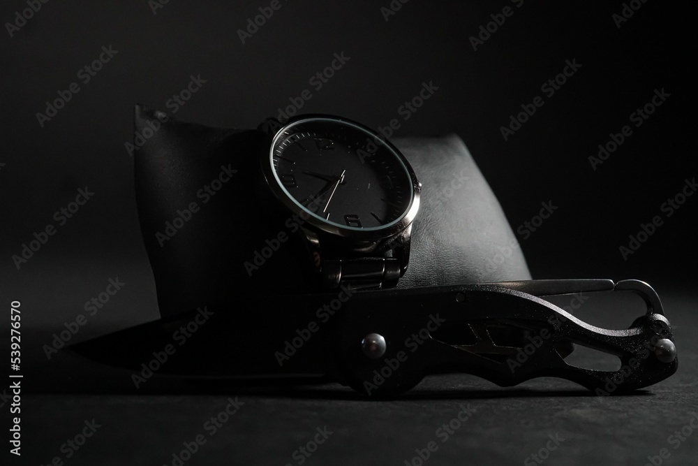 Closeup shot of a men's elegant wristwatch and pocket knife - obrazy, fototapety, plakaty 