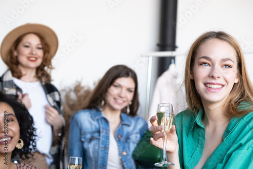 Four beautiful happy caucasian and african american women drinking champagne at home exchange party. Choose casual clothes, shoes, hats, bags, jewelry