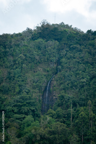 Waterfall Between the Mountains full of Vegetation on a Cloudy Day
