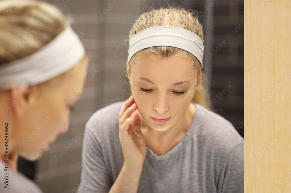 woman looking in the mirror in the bathroom and taking care of her skin. woman looking in the mirror in the bathroom and taking care of her skin.