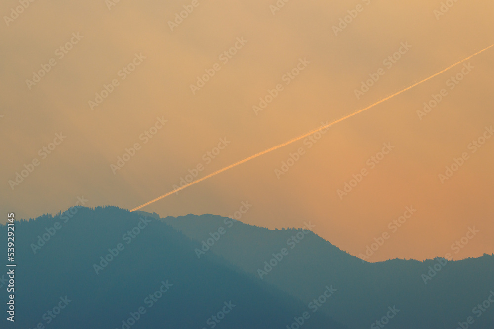 Airplane vapor trail in smokey sky