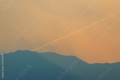 Airplane vapor trail in smokey sky