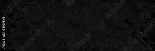 Black stone texture. Old rough cracked wall surface. Close-up. Dark grunge background  backdrop with space for design. Banner. Wide. Long. Panoramic. Template. Empty.