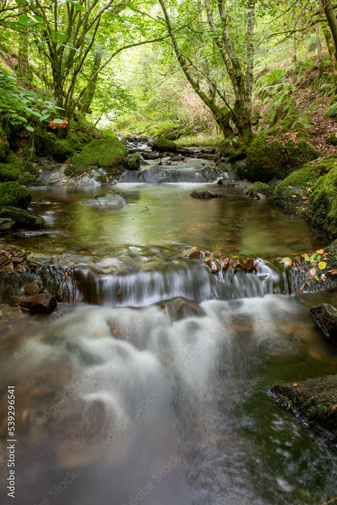 Long exposure of a waterfall on the Horner Water river in Horner woods in Somerset