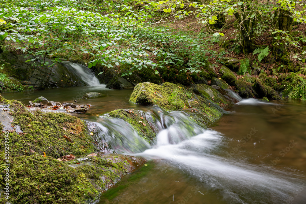 Long exposure of a waterfall on the Horner Water river in Horner woods in Somerset Long exposure of a waterfall on the Horner Water river in Horner woods in Somerset