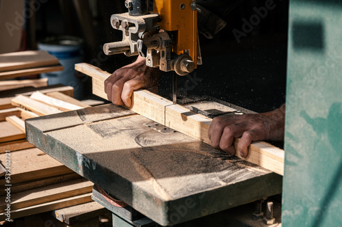 Worker in the carpentry workshop cuts the log into boards using band saw. Joinery. Raw wood Wooden crafts. Work at the factory. Working band sawmill in action, close-up. 