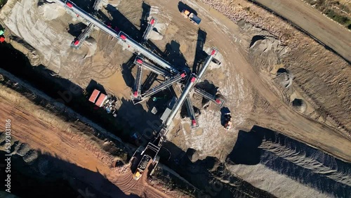 Bird's eye view over a quarry plantation with cranes and tractors digging the ground on a sunny day photo