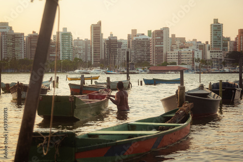 hombre dentro del entre botes al atardecer con edificios al fondo  © Bruno