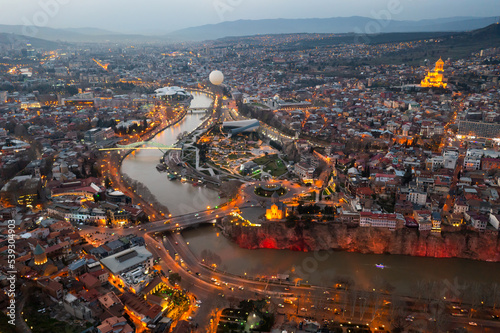 Picturesque general view from drone of Georgian city of Tbilisi on banks of Mtkvari River at spring dusk