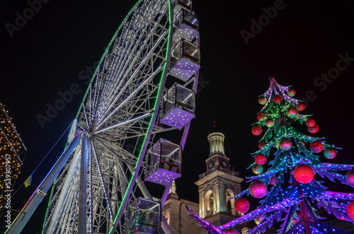 Ferris wheel and New Year tree, at traditional Christmas fair on Kontraktova Square. Winter holiday in Kyiv, Ukraine photo