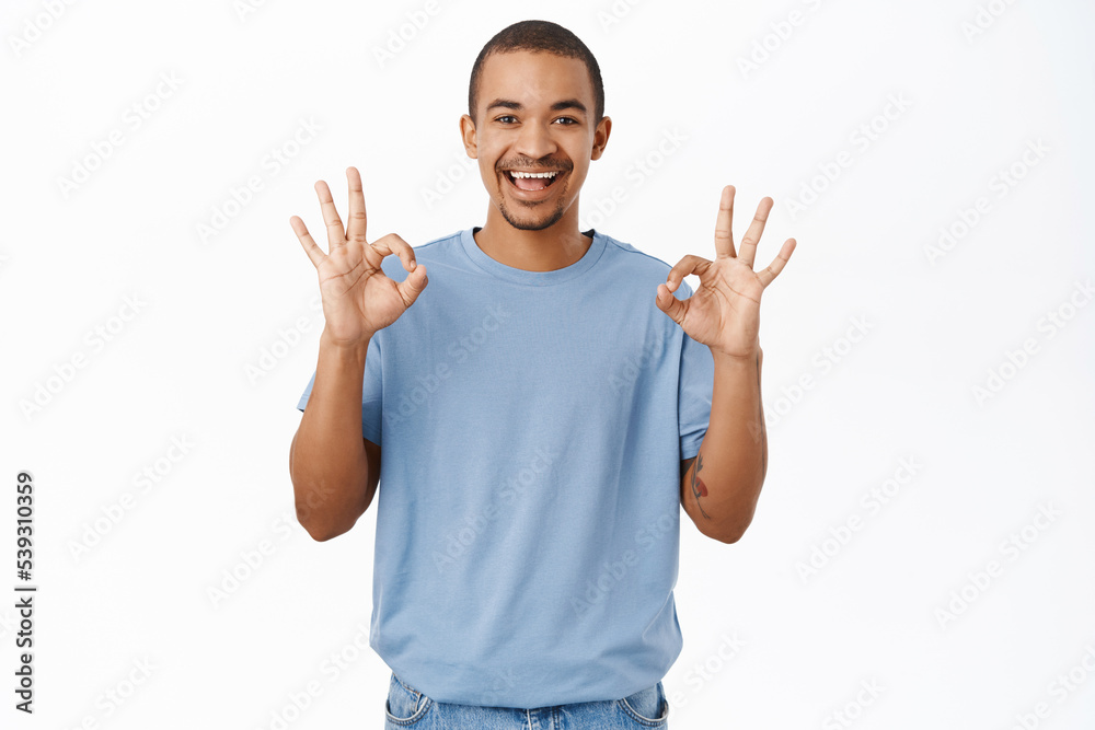 Nice, not bad. Smiling arab man shows okay, ok sign, recommends smth awesome, stands over white background Nice, not bad. Smiling arab man shows okay, ok sign, recommends smth awesome, stands over white background