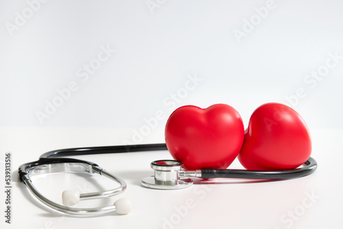 two red hearts surrounded by a stethoscope on white background
