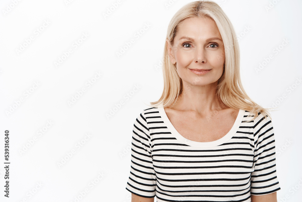 Close up of smiling grandmother, elegant senior woman with blond hair, white smile, stands over white background Close up of smiling grandmother, elegant senior woman with blond hair, white smile, stands over white background