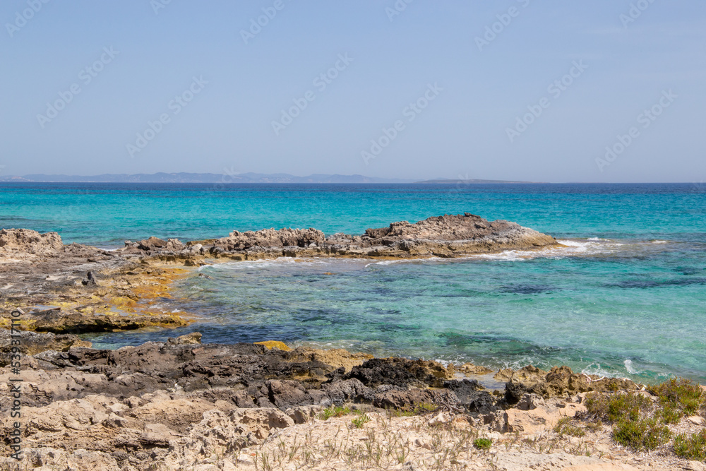 Rocky beach with a turquoise blue sea and waves in spain