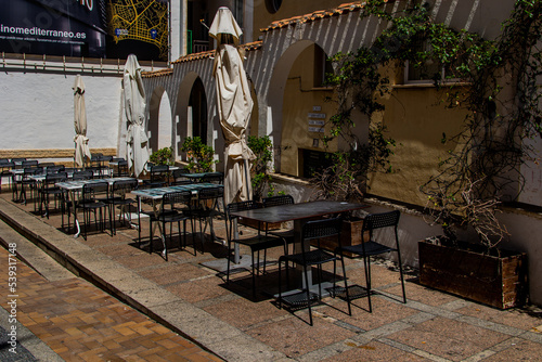  l urban landscape of a Spanish street in Benidorm with a cafe and tables on the sidewalk without people