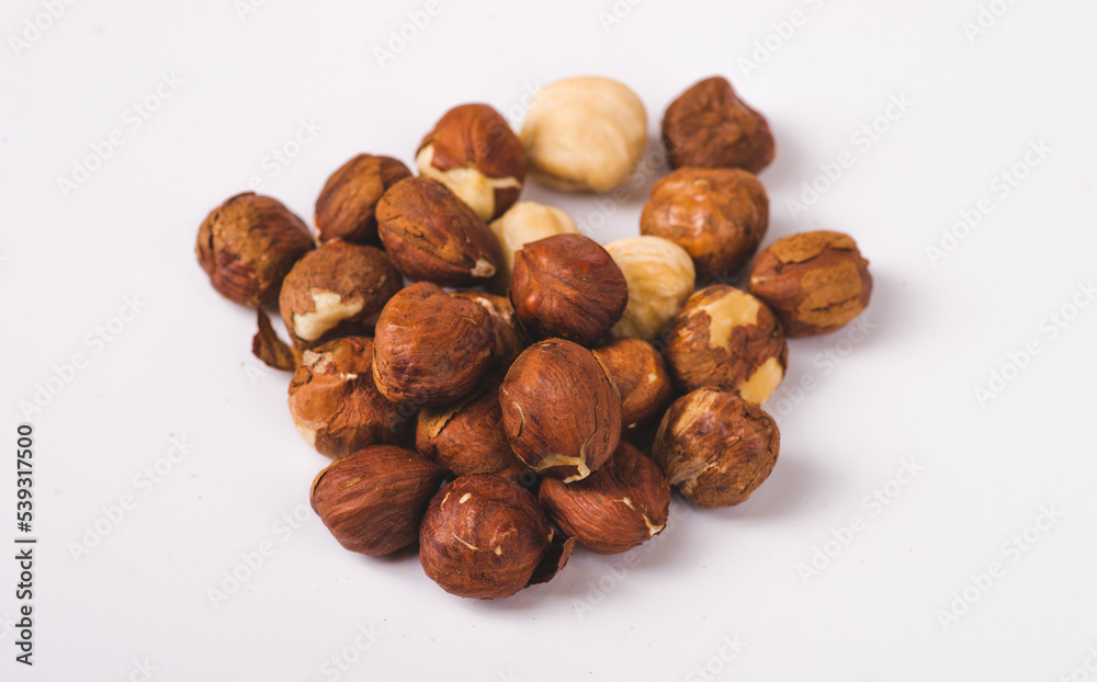 Pile of roasted peeled hazelnuts close-up isolated on white background. Lots of brown nut seeds, healthy vegan and vegetarian food Pile of roasted peeled hazelnuts close-up isolated on white background. Lots of brown nut seeds, healthy vegan and vegetarian food