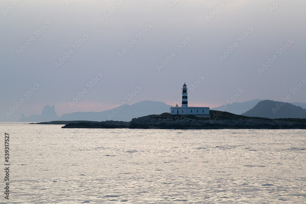 Lighthouse on a Mediterranean island during sunset.