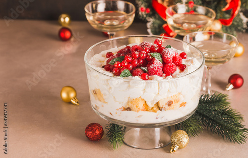 Christmas trifle with panettone and cream with berries on festive table copy space background. photo