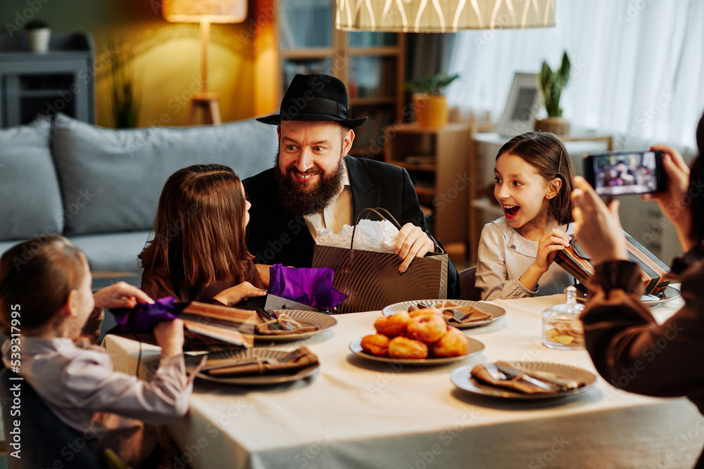 Portrait of modern jewish family sharing gifts at dinner table in cozy home setting