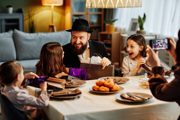 Portrait of modern jewish family sharing gifts at dinner table in cozy home setting