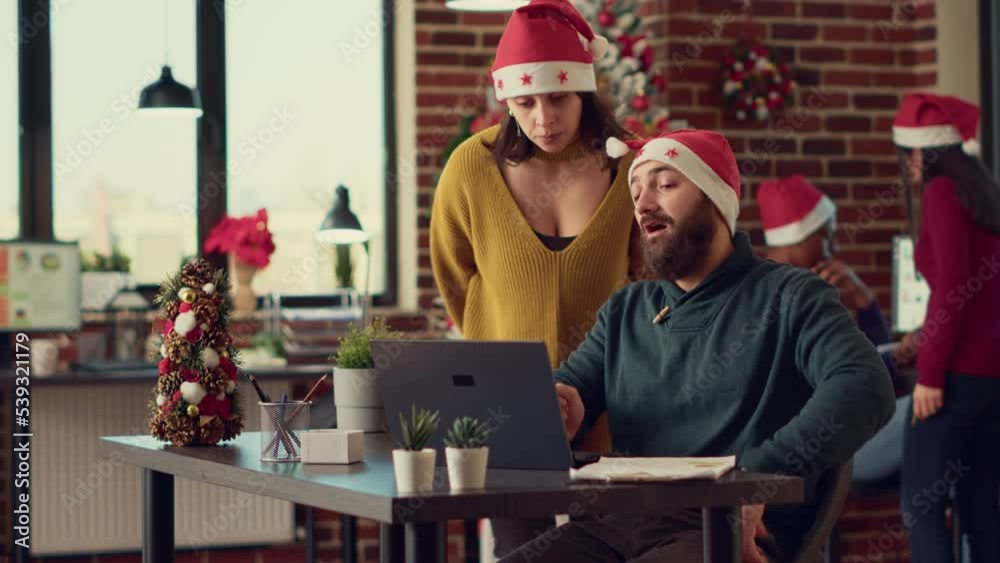 Team of people looking at data research on laptop, working in office with festive decorations. Doing startup teamwork during christmas eve time in workplace with holiday ornaments. Team of people looking at data research on laptop, working in office with festive decorations. Doing startup teamwork during christmas eve time in workplace with holiday ornaments.