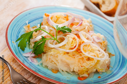 Plate with appetizing sauerkraut, carrots and onion. Traditional russian dish