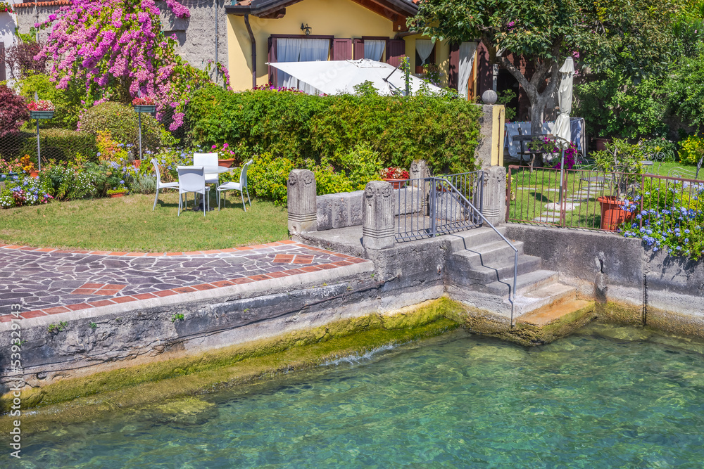 Garden with flowers in back yard at sunny springtime, Lake Garda, Italy