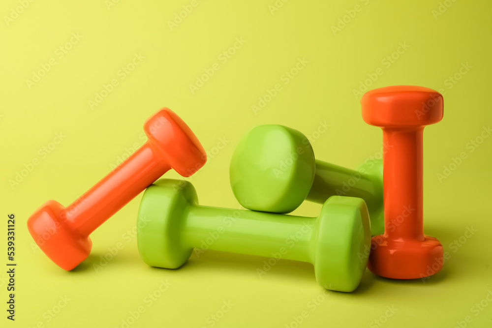 Many different stylish dumbbells on light green background Many different stylish dumbbells on light green background